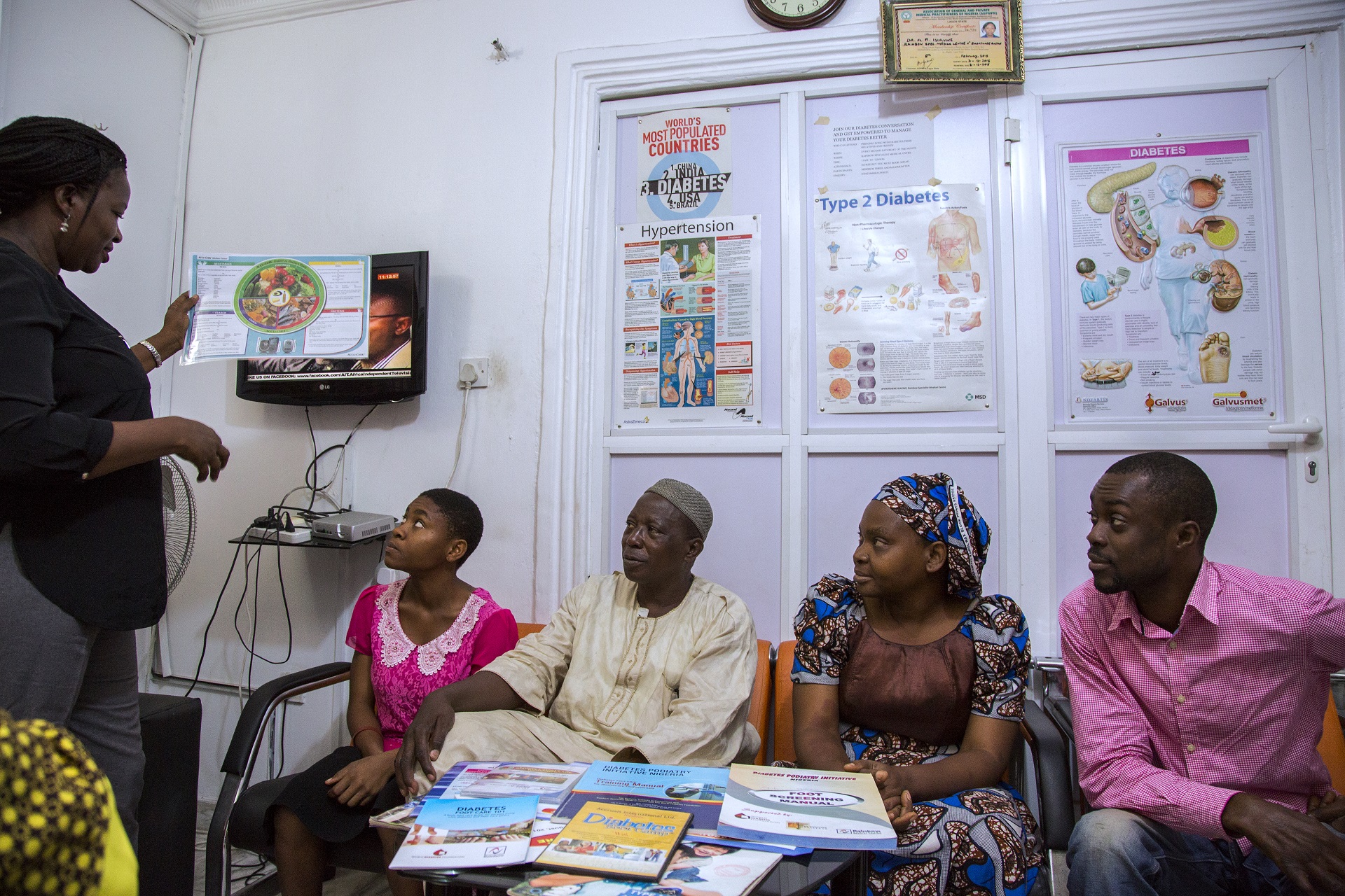 A health activist standing 4 people sitting watching a presentation